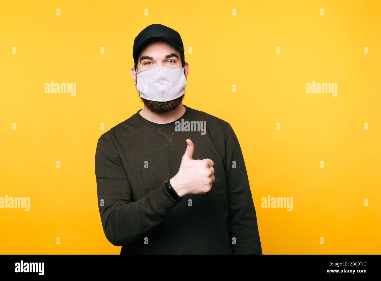 Download Portrait Of Young Man With Facial Mask Showing Thumbs Up Gesture Over Yellow Background Stock Photo Alamy PSD Mockup Templates