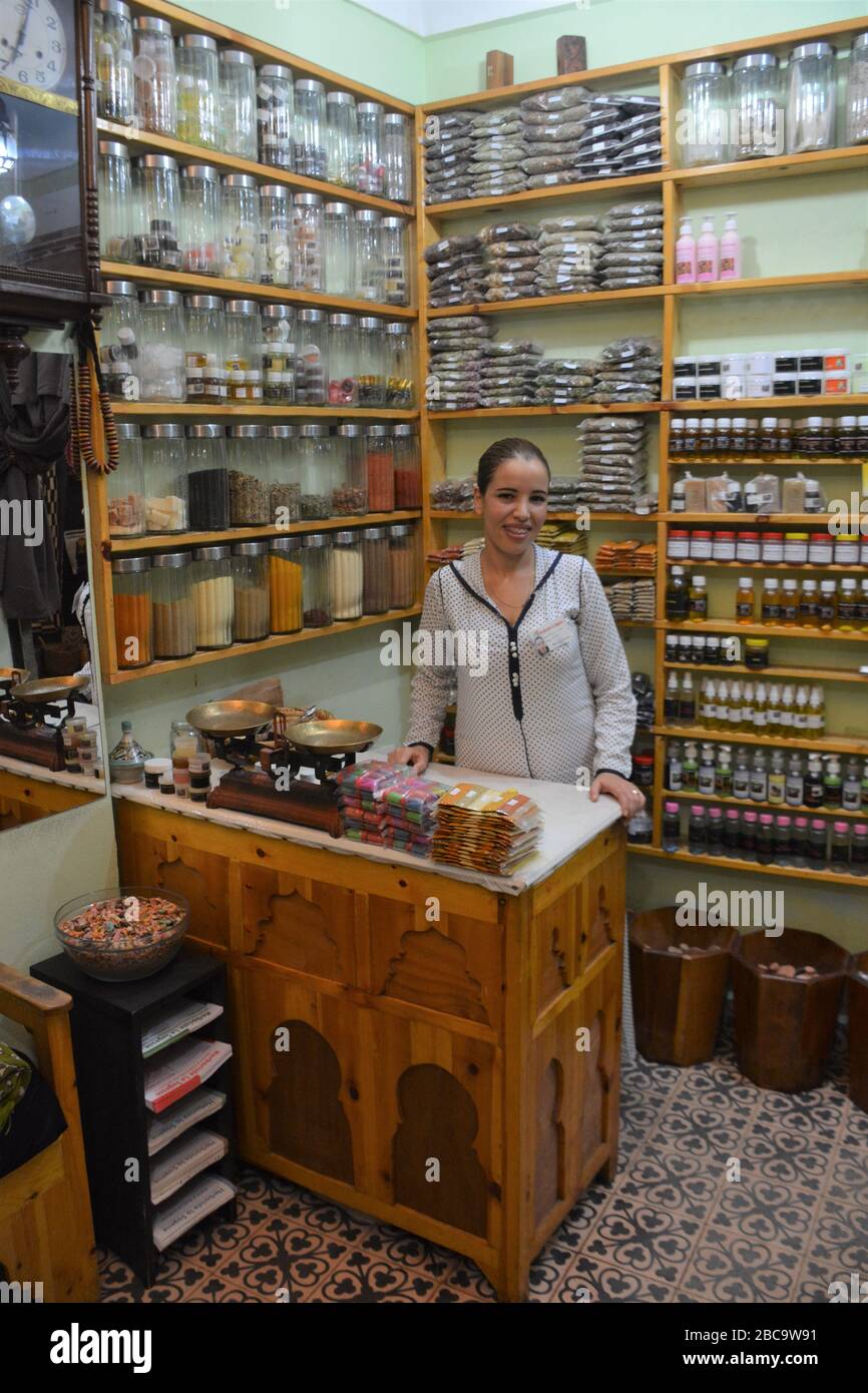 A herbalist stands amid myriad jars of medicinal plants, teas, creams