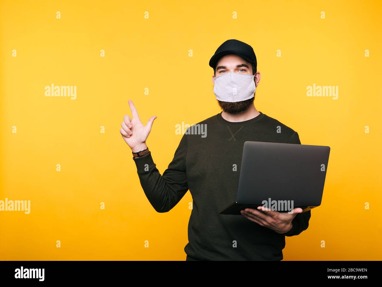 Download Portrait Of Young Man With Facial Mask Using Laptop And Pointing Away Over Yellow Background Stock Photo Alamy PSD Mockup Templates