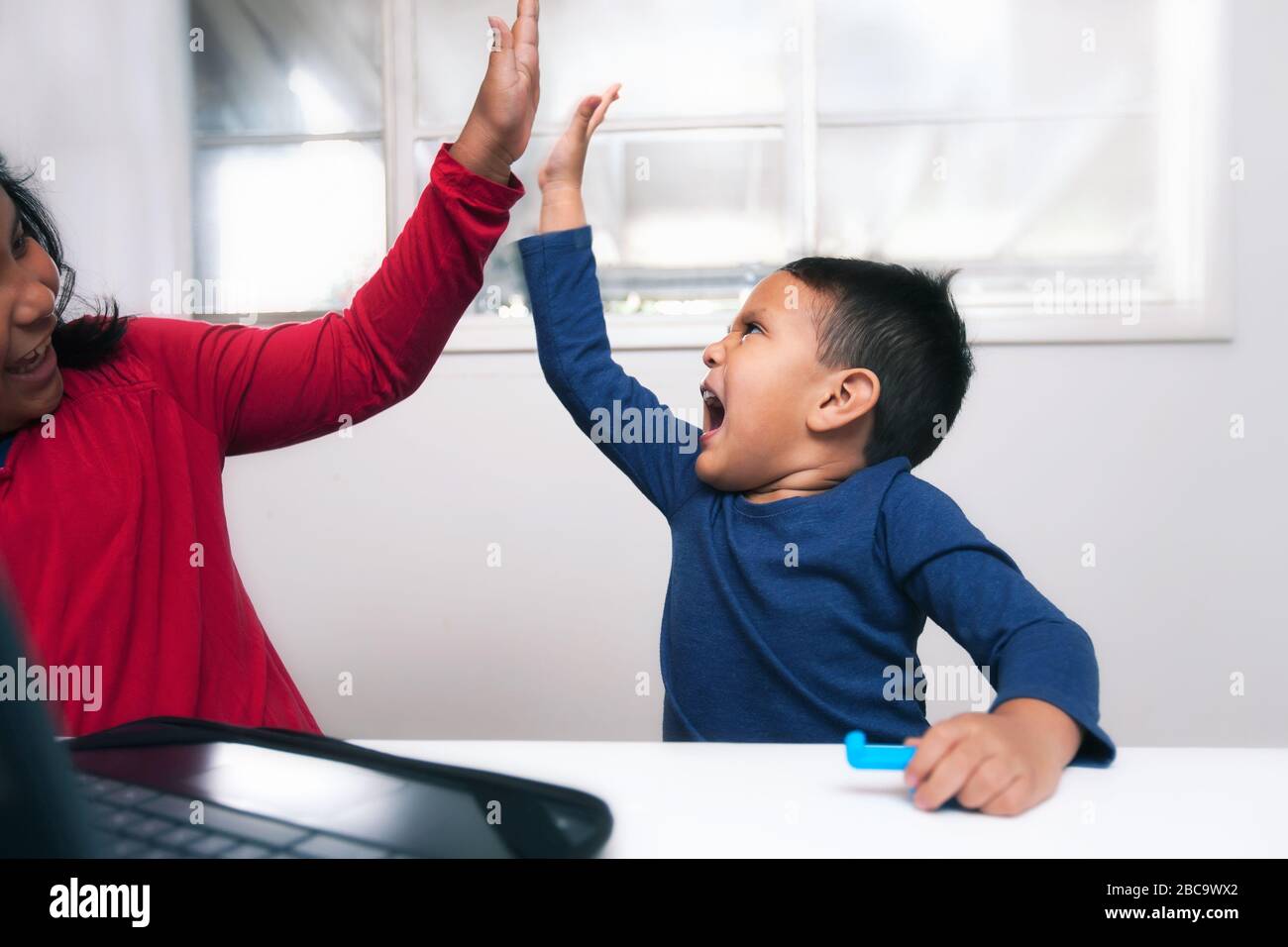 Brother and sister learning together and committed to distance learning in light of school closure. Stock Photo