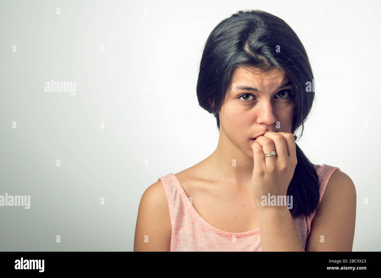 Portrait of a teenager brunette girl with nervous expression and nail-biting Stock Photo