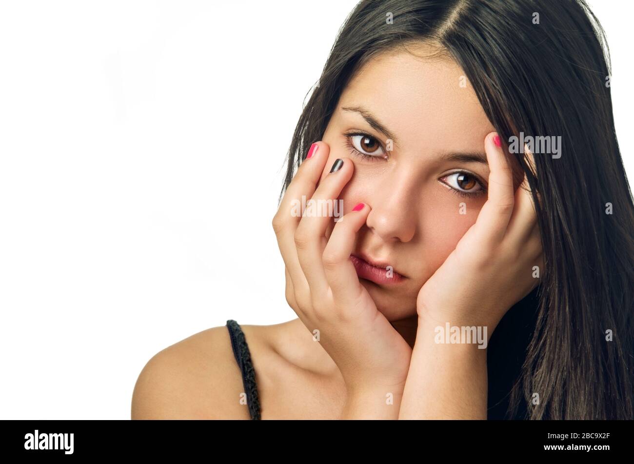 Beautiful serene teenage girl with hands on face isolated in white background Stock Photo