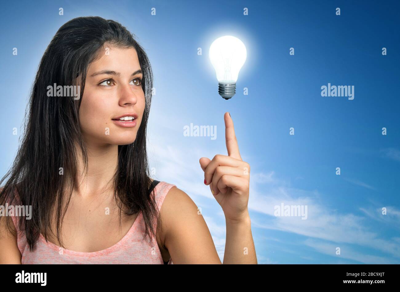 Teenager brunette girl pointing her finger to a light bulb Stock Photo