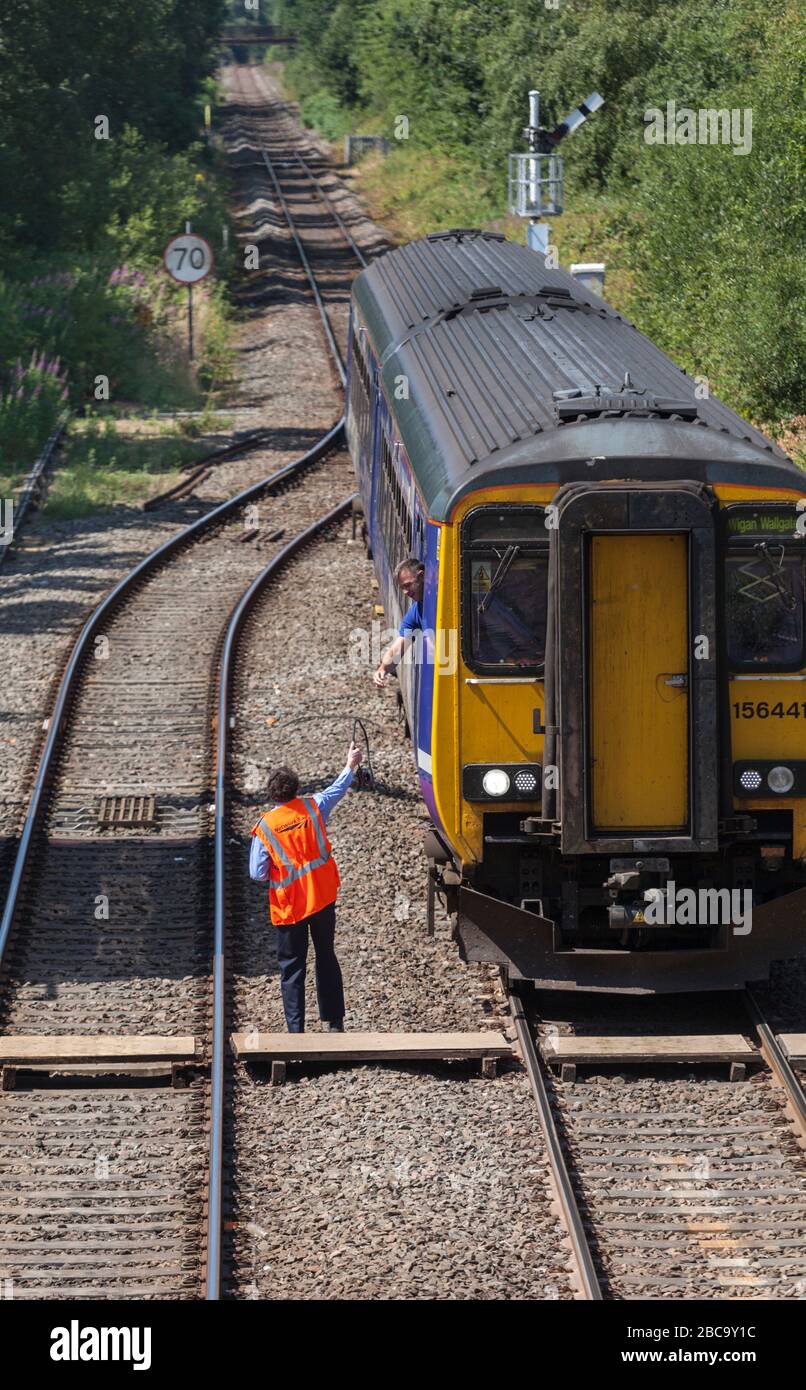 Northern Rail / Northern Trains class 156  train 156441 at Rainford   junction signalbox with the signal man collecting the single line token Stock Photo