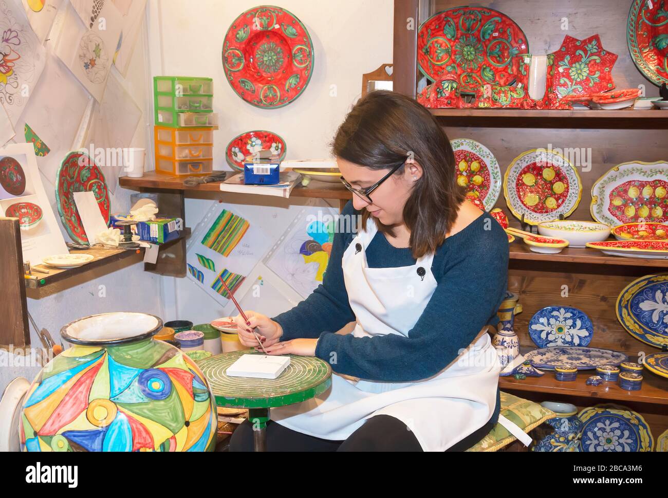 A craftswoman hand painting traditional ceramics, Erice, Sicily, Italy