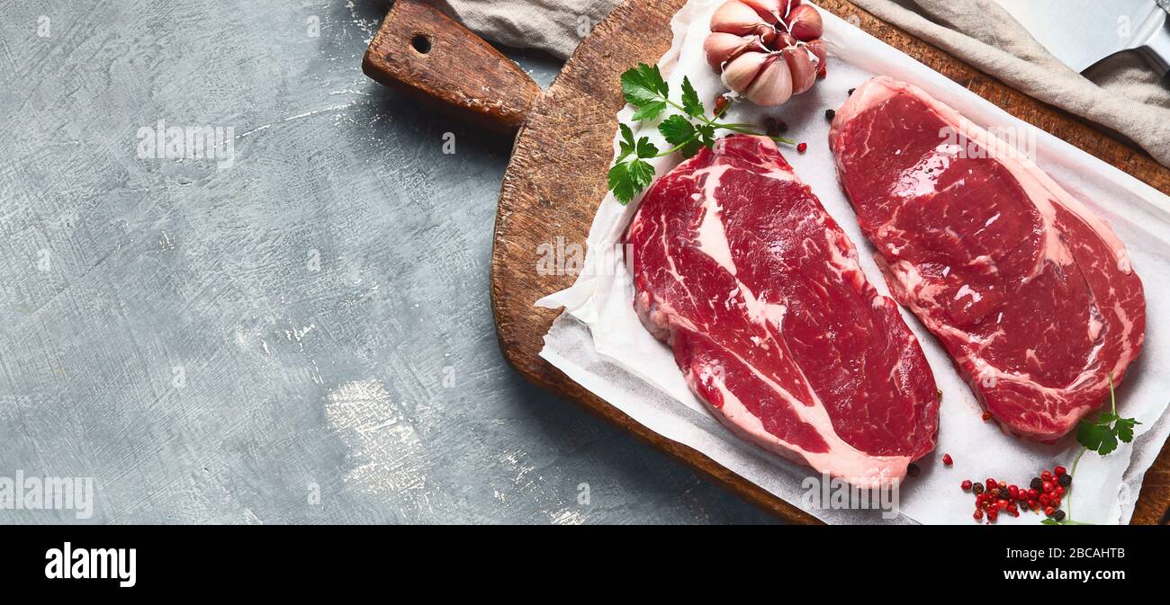 Raw beef steaks on wooden cutting board. Top view with copy space