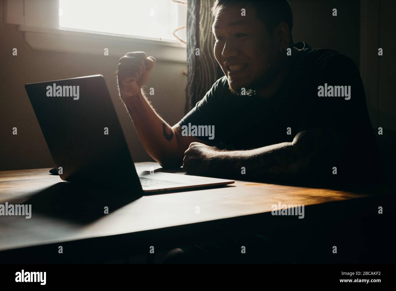 A asian man working  on laptop in dark area. Happy gesture. Stock Photo