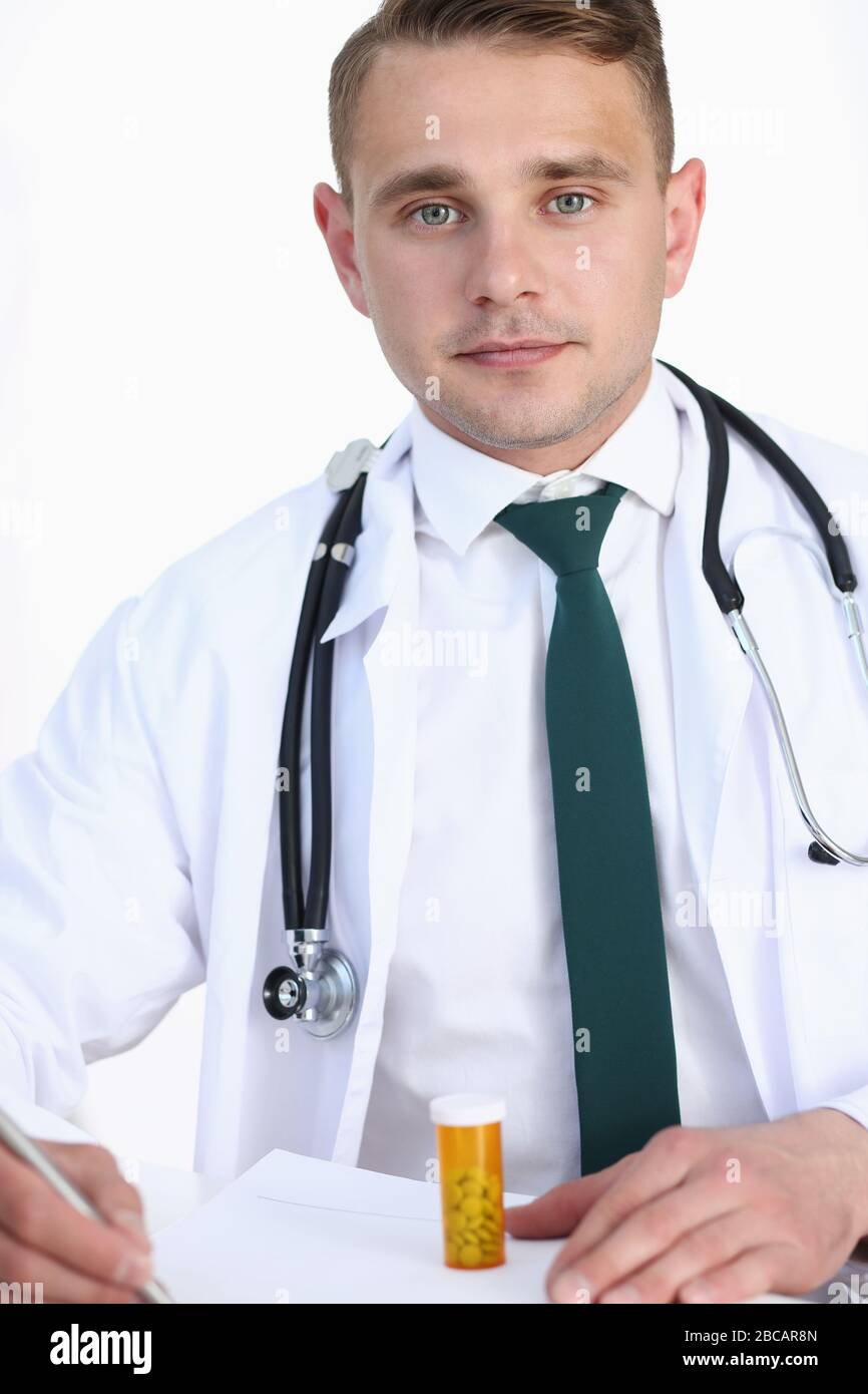 Handsome smiling male doctor write prescription at workplace Stock ...