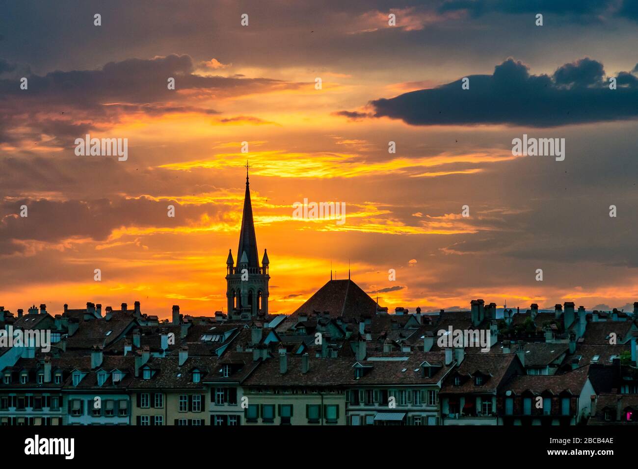 The clouds over the old town of Bern and the Nydeggkirche shine orange. Stock Photo