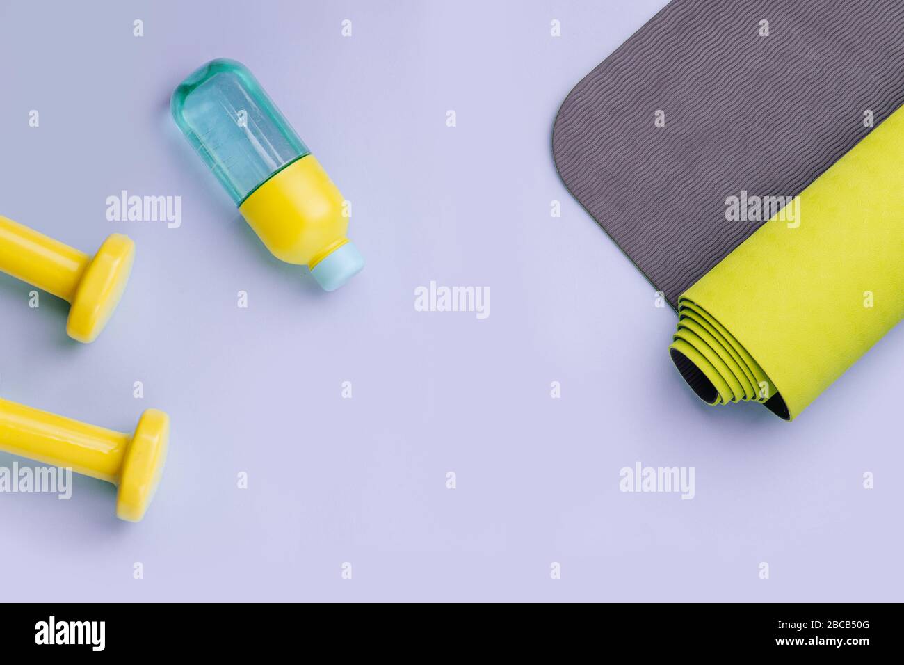 Dumbbells, bottle of water and a rolled mat spread out. Copy space. Top