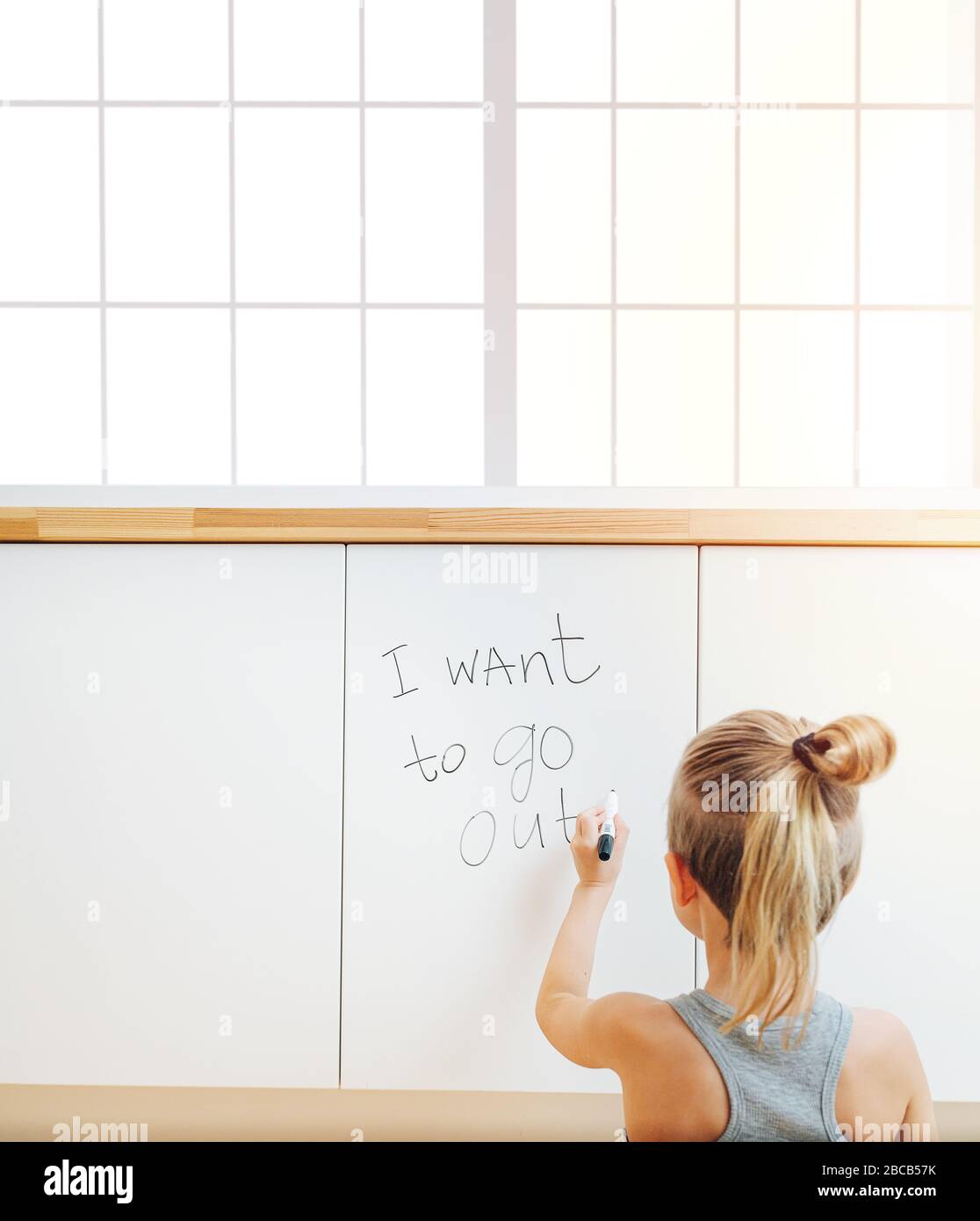 Little boy writing on a board that he want's to go outside Stock Photo