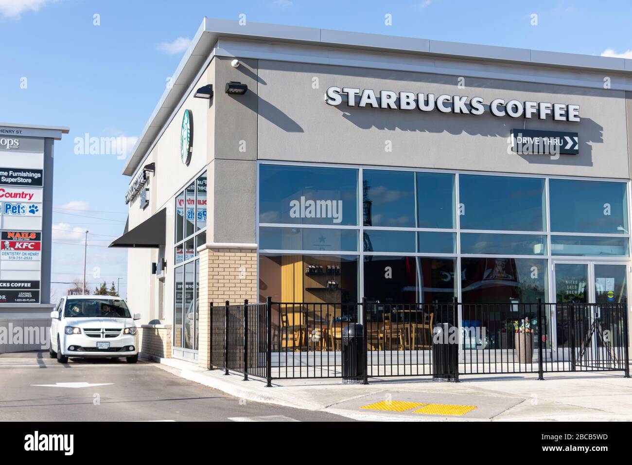 Car waits at drive-thru window as empty Starbucks Coffee café due to the COVID-19 pandemic, seen on sunny day. Stock Photo