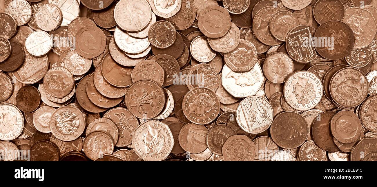 UK currency, hundreds of British copper and silver colored coins randomly piled ontop of each other, one pound coins, fifty pence, twenty pence, two p Stock Photo