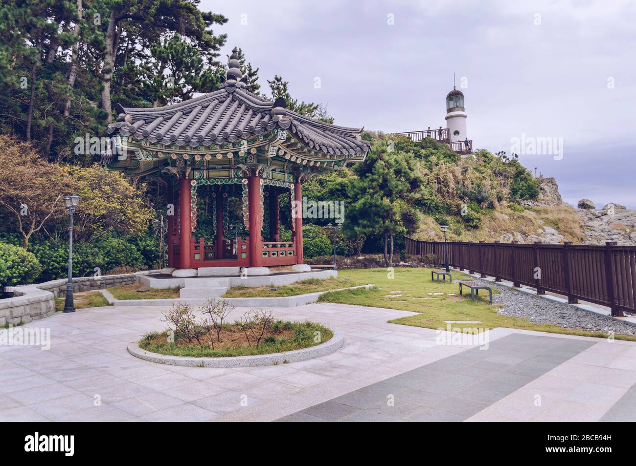 traditional korean pavilion on grounds of Nurimaru APEC house with overcast skies and lighthouse on background Stock Photo