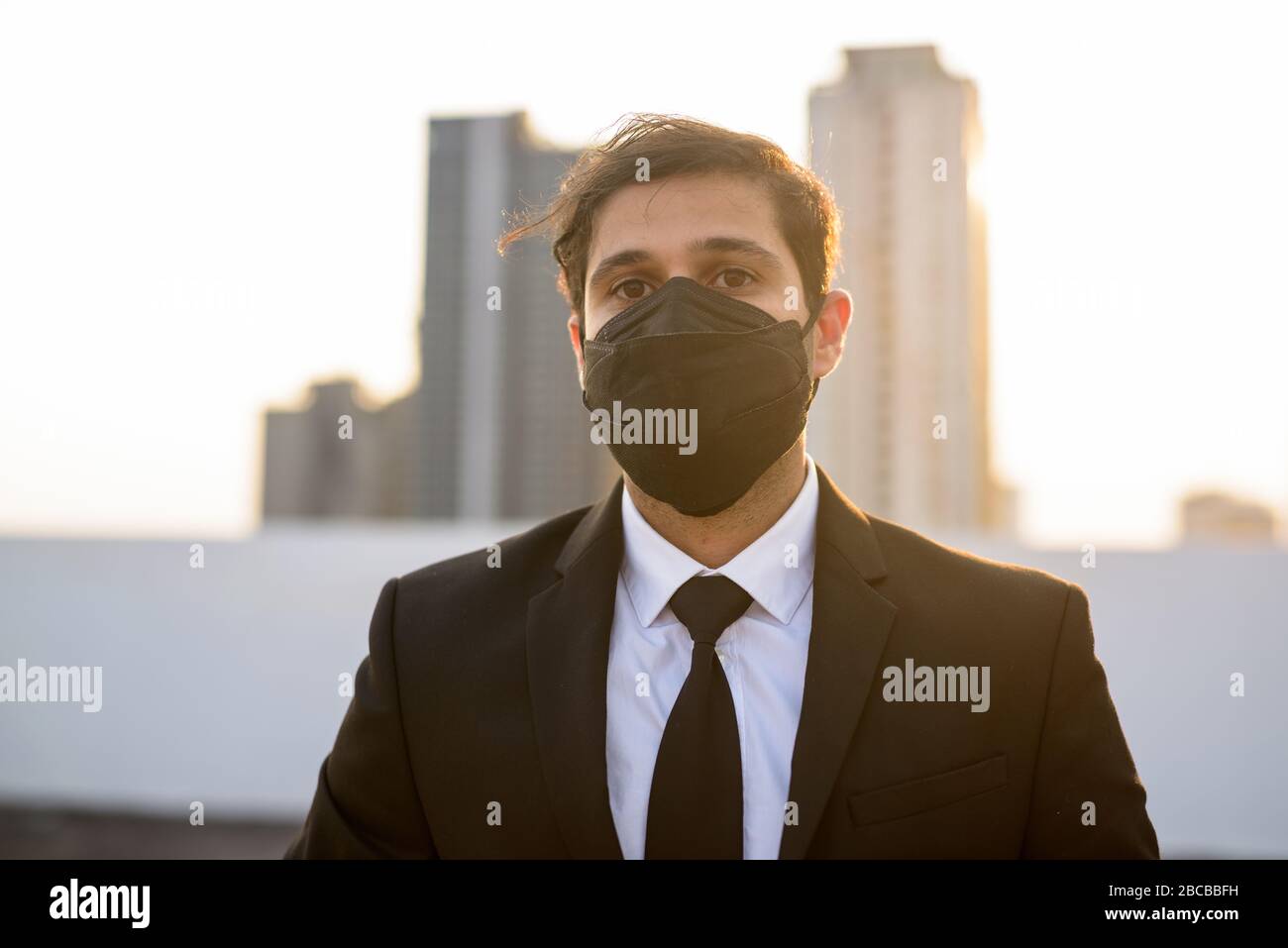 Young Persian businessman wearing mask for protection from corona virus outbreak and pollution Stock Photo