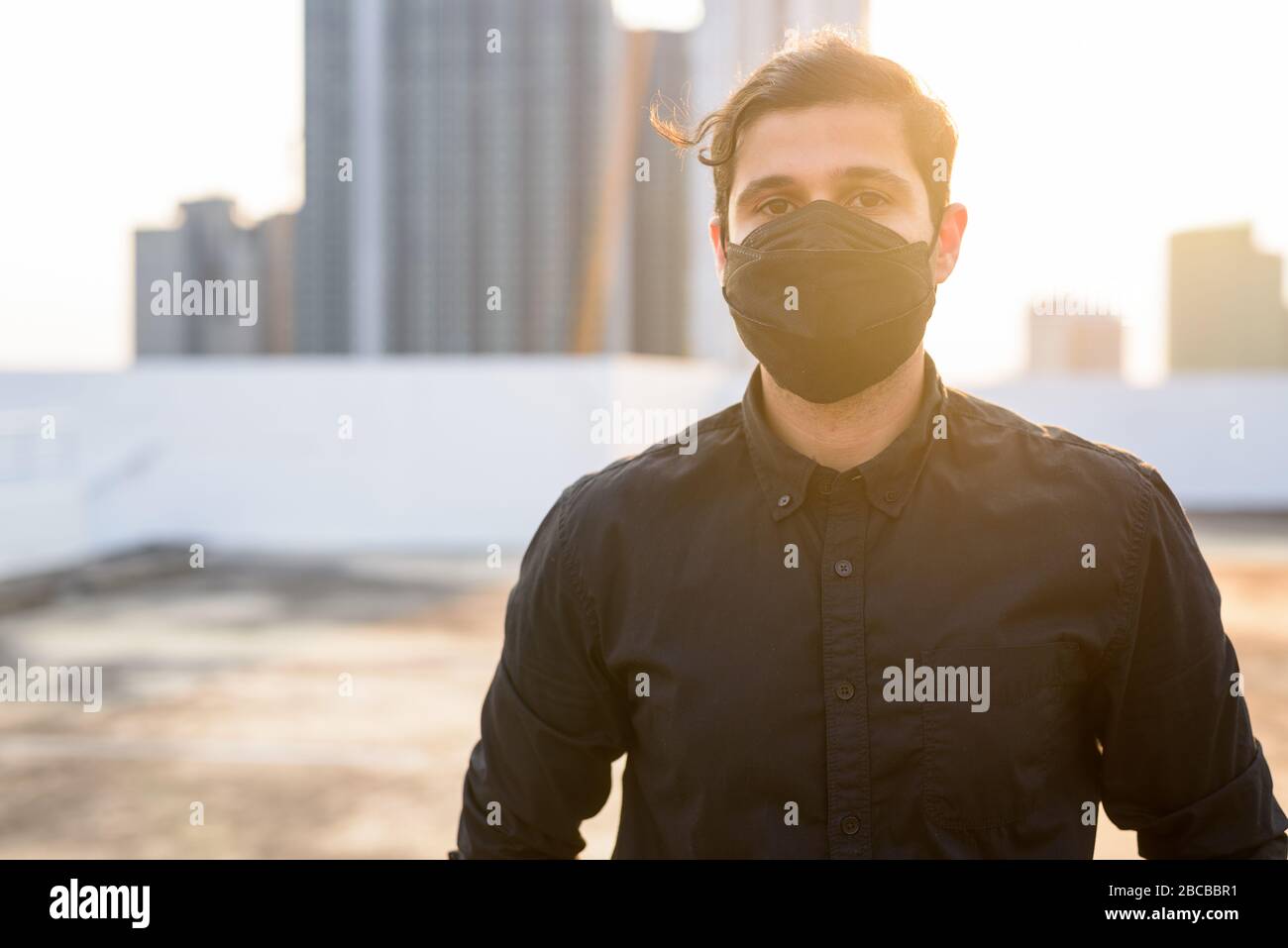 Young Persian businessman wearing mask for protection from corona virus outbreak and pollution Stock Photo