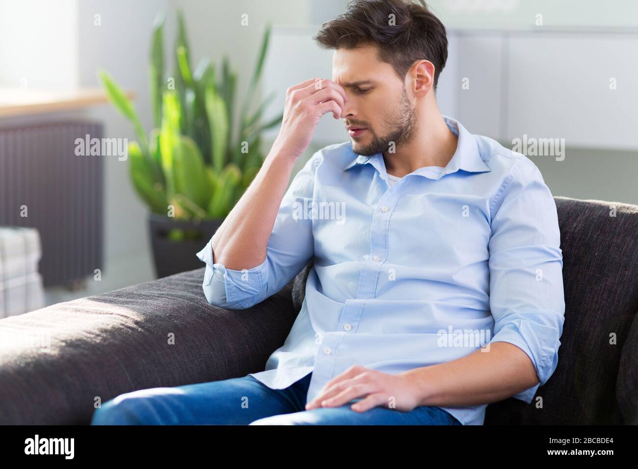 Man On Sofa Having Headache Stock Photo