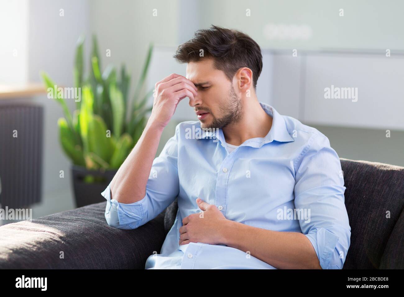 Man On Sofa Having Headache Stock Photo