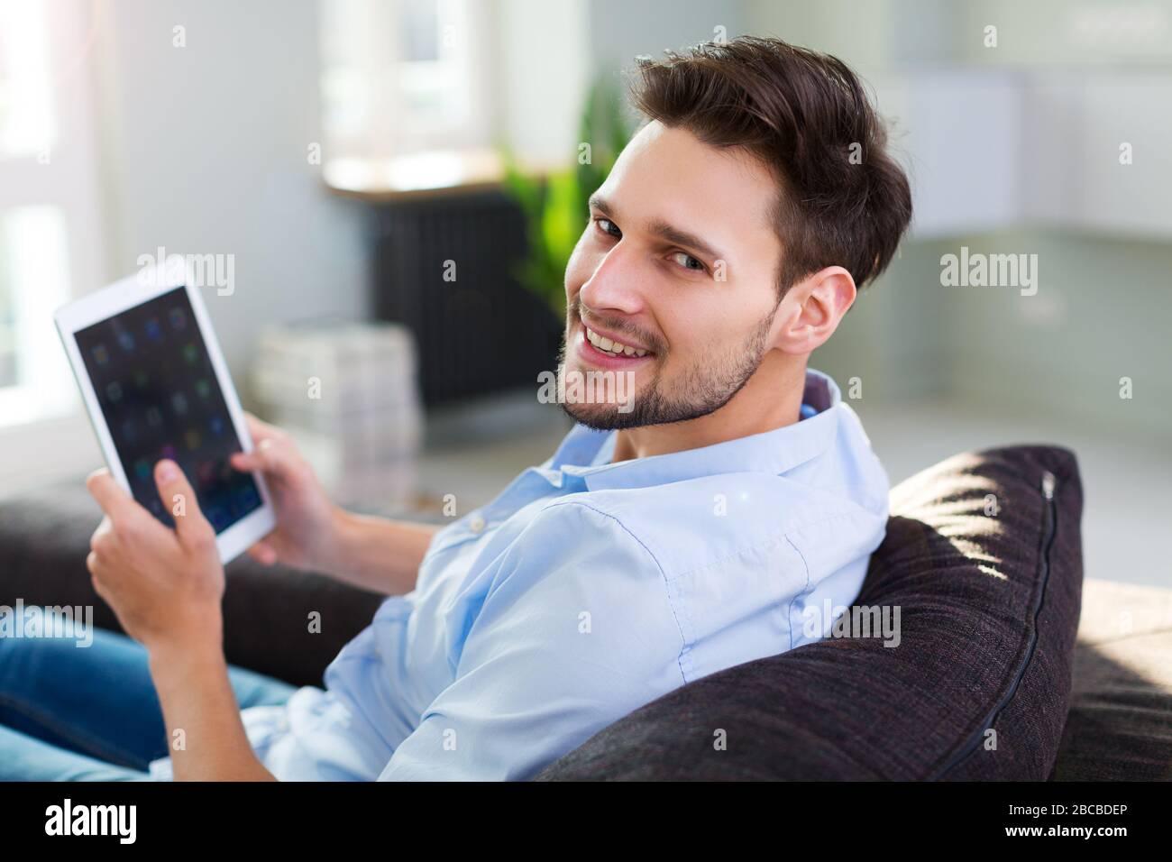 Man sitting on couch with digital tablet Stock Photo
