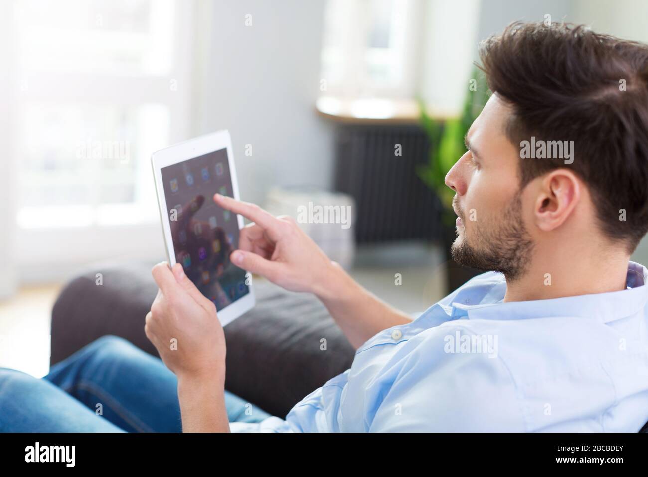 Man sitting on couch with digital tablet Stock Photo
