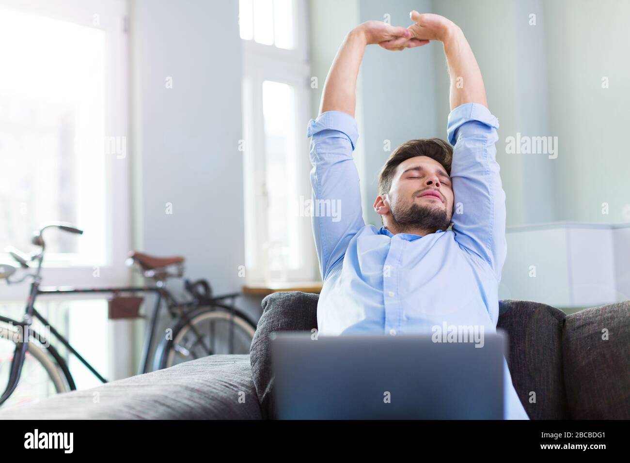 Man sitting on couch with laptop Stock Photo
