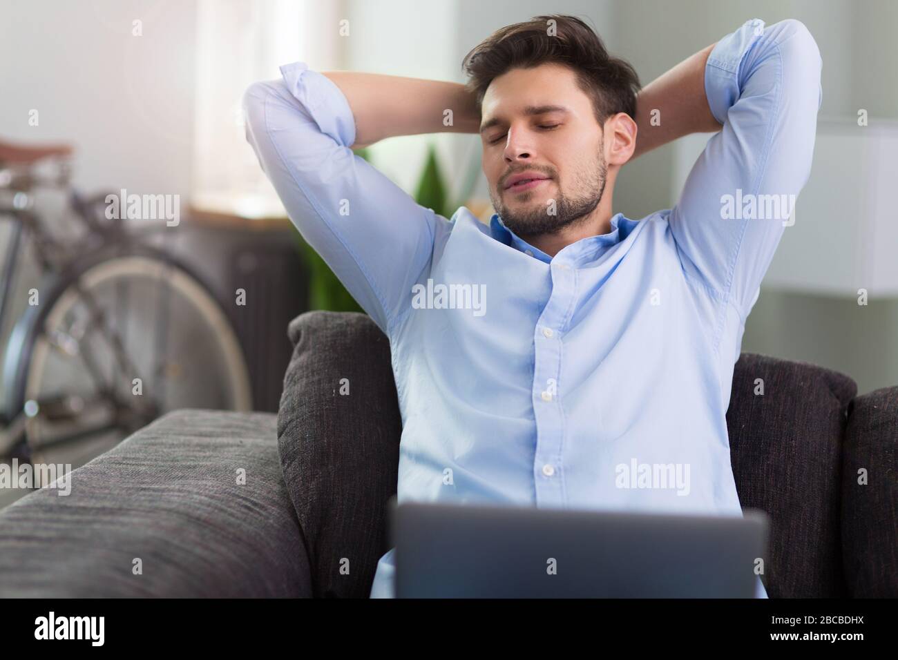 Man sitting on couch with laptop Stock Photo