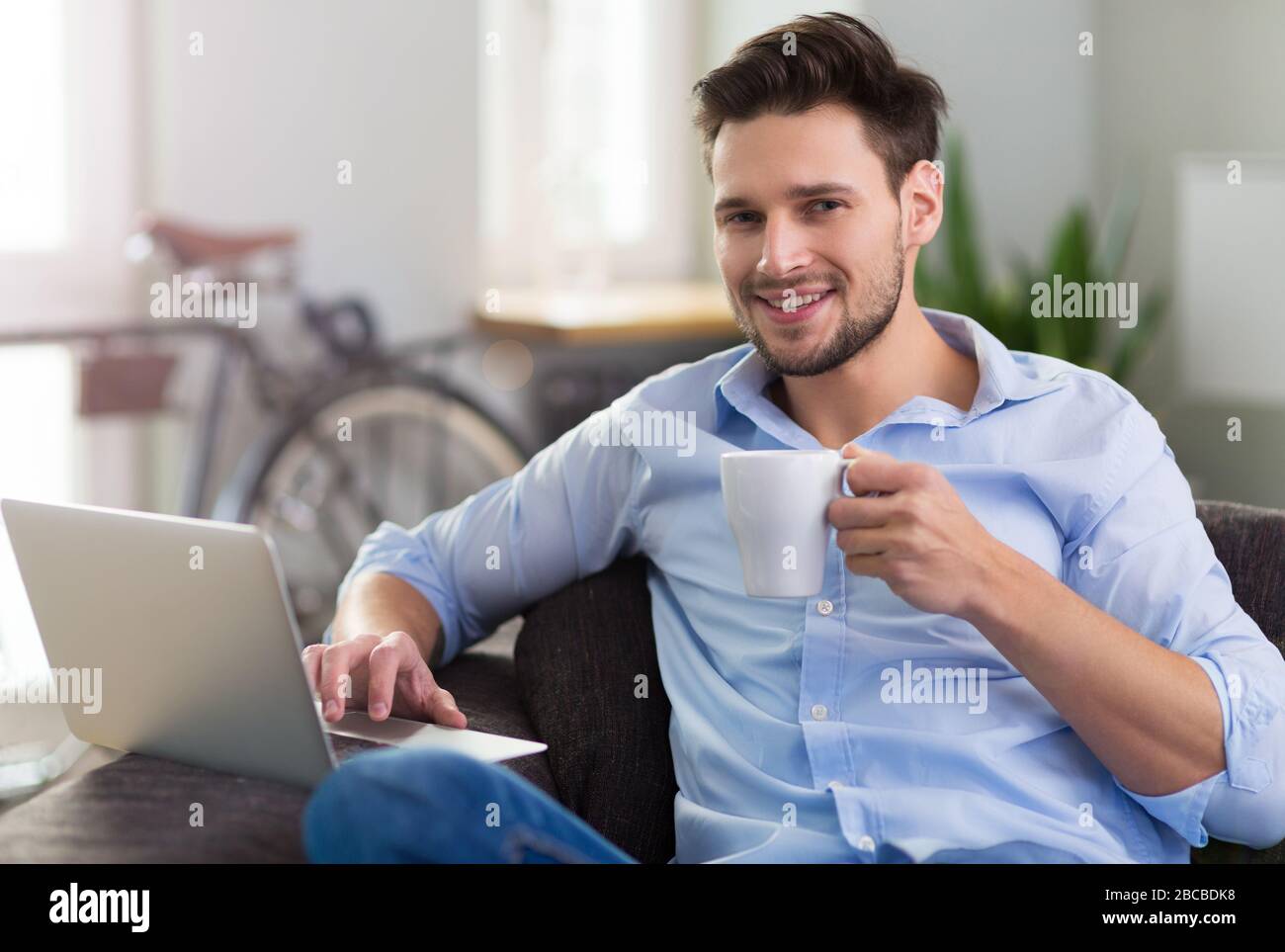 Man sitting on couch with laptop Stock Photo