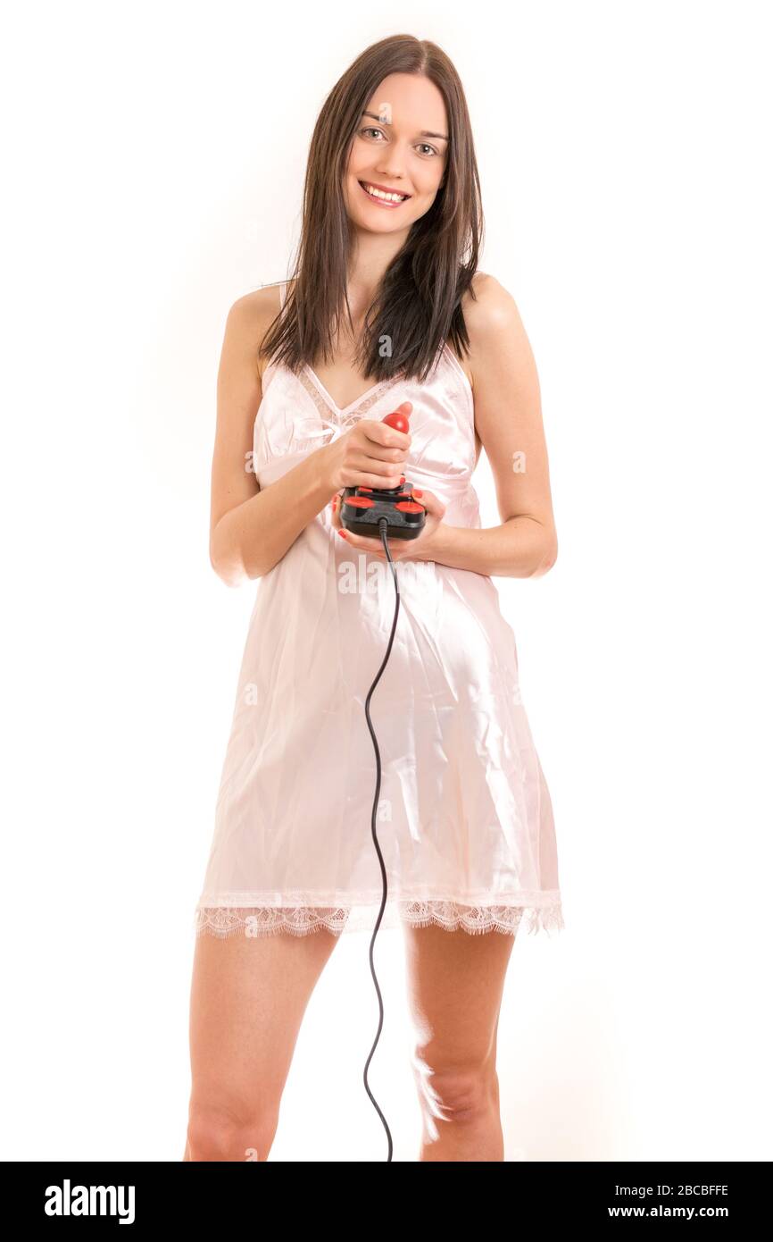 Attractive young brunette woman wearing a pink nightgown, holding a joystick smiling. Royalty free stock photo. Stock Photo