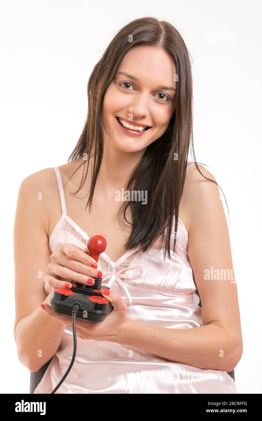 Attractive young brunette woman wearing a pink nightgown, having fun holding a joystick. Royalty free stock photo. Stock Photo