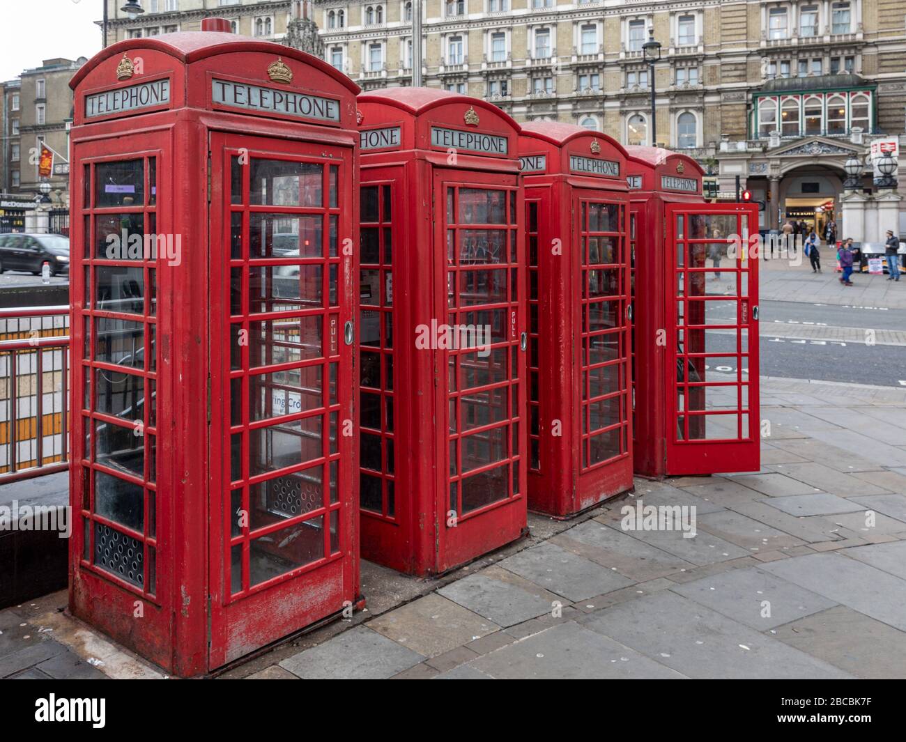 Four red traditional and heritage telephone boxes stand in a row on the Strand, London, England, UK opposite Charing Cross Station. Stock Photo