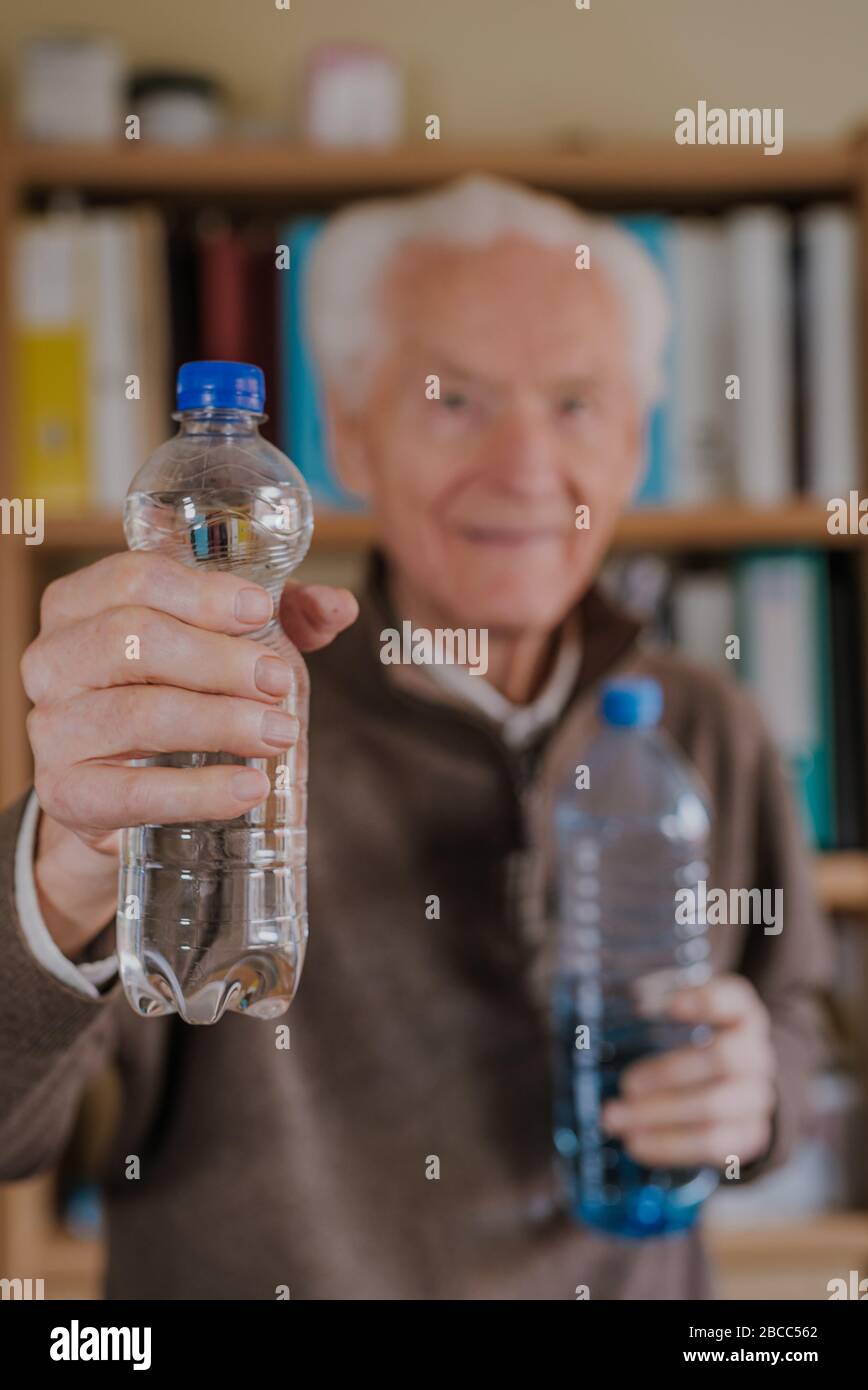 Smiling Old man holding plastic water bottles. Caring for good