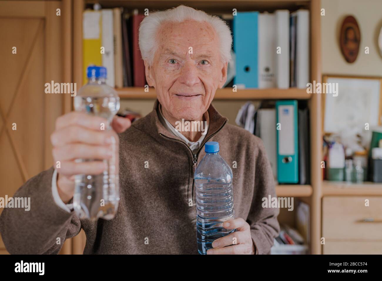 Smiling Old man holding plastic water bottles. Caring for good