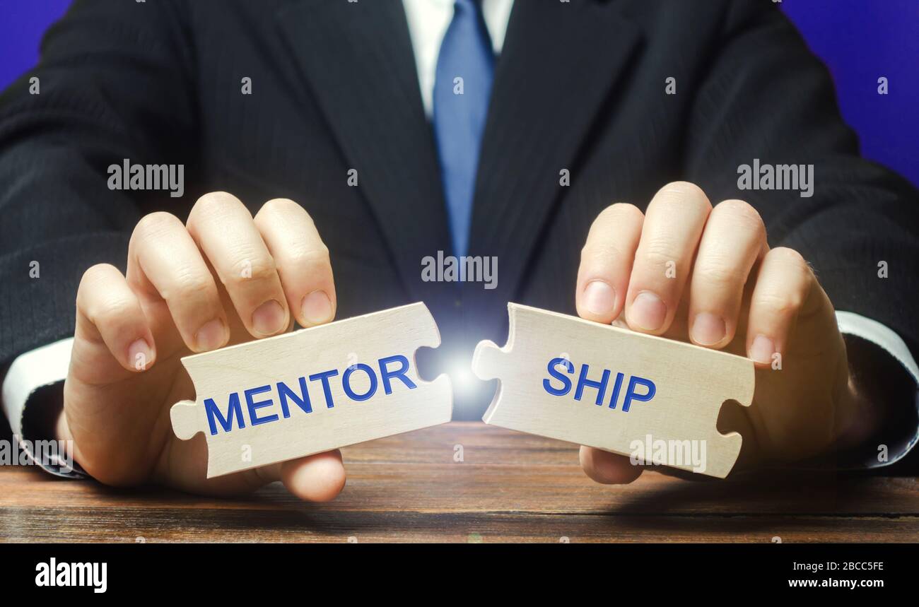 Businessman collects wooden puzzles with the words Mentorship. Business support. The concept of personal and professional development and training by Stock Photo