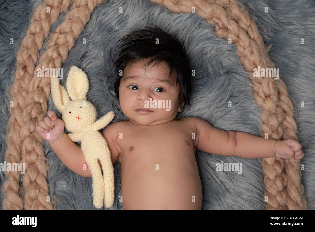 Little baby with teddy bear lying on the fur bed stock photo Stock Photo