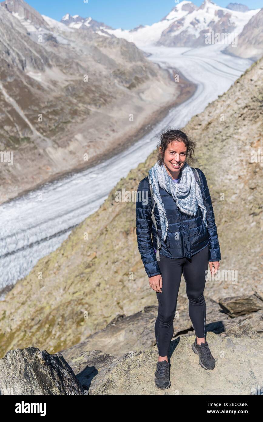 Young Caucasian woman posing for the camera, with the Great Aletsch Glacier behind her Stock Photo