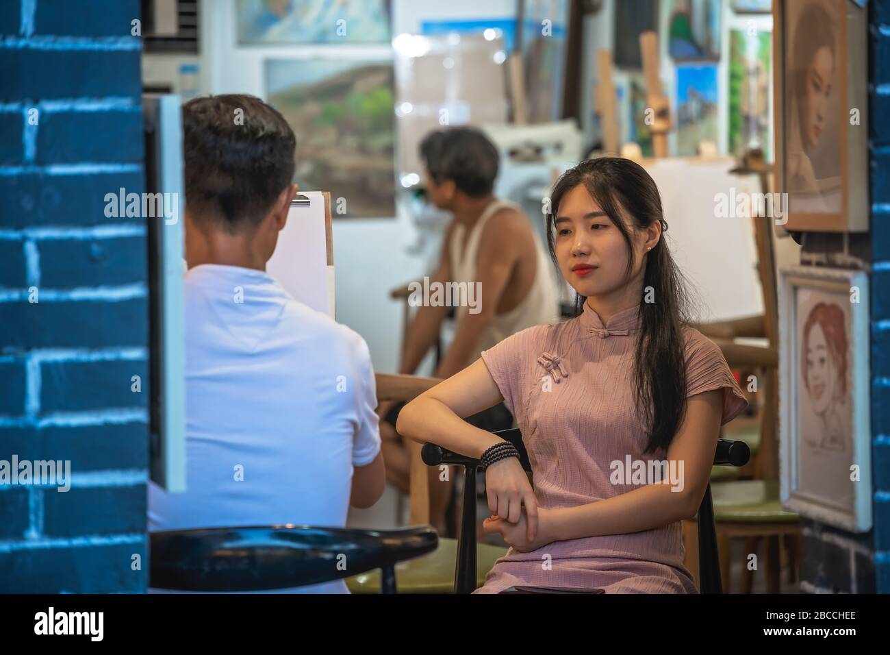 Chongqing, China -  August 2019 : Male artist drawing portraits of chinese woman customer in his art studio gallery in the Ci Qi Kou Ancient town Stock Photo