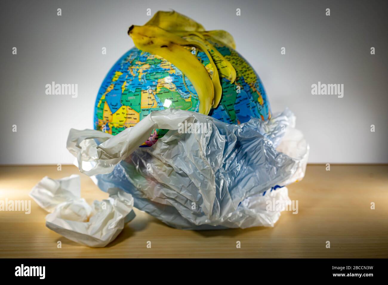 plastic with planet earth inside and some garbage like paper and banana  leftovers on top of the earth. Earth is being destroyed because of too much  pl Stock Photo - Alamy
