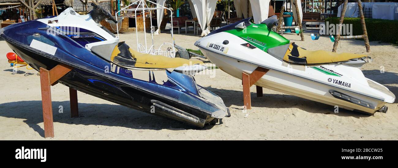 Two Colorful Jet Ski Parked On The Beach Of Holiday Season. Old Jet Skis On The Beach On Wooden Trailer. Blue And White Jet Ski - Dubai Uae January 20 Stock Photo