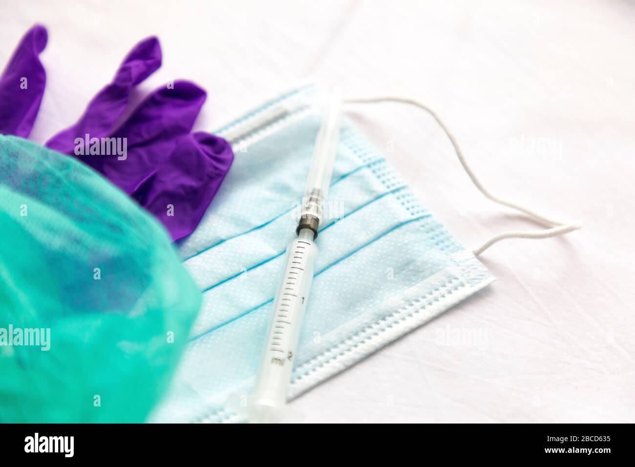 Gloves, mask and syringe with needle on a white background. Protective agents against viruses, bacteria. Stock Photo