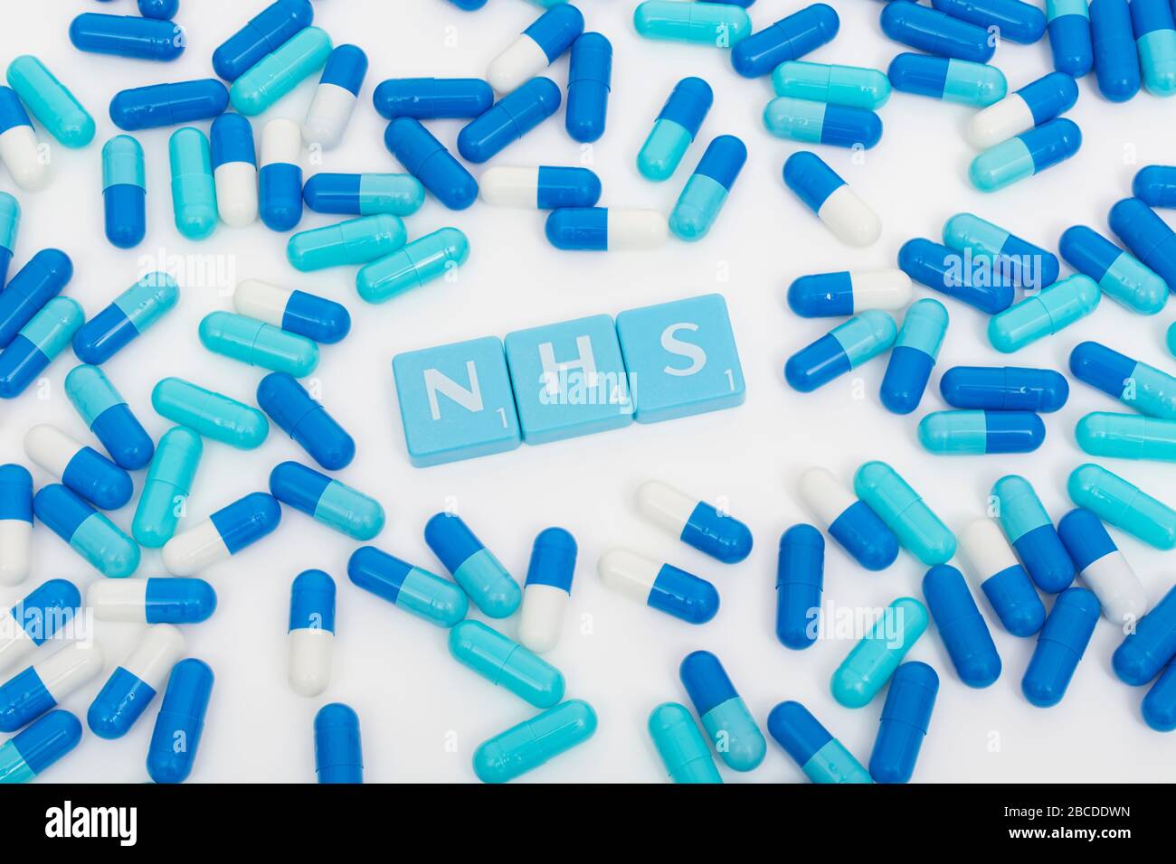 NHS letters tiles & assorted blue pills. Metaphor NHS in Covid 19 pandemic, NHS heroes, NHS prescriptions, UK National Health Service, medicine in UK Stock Photo