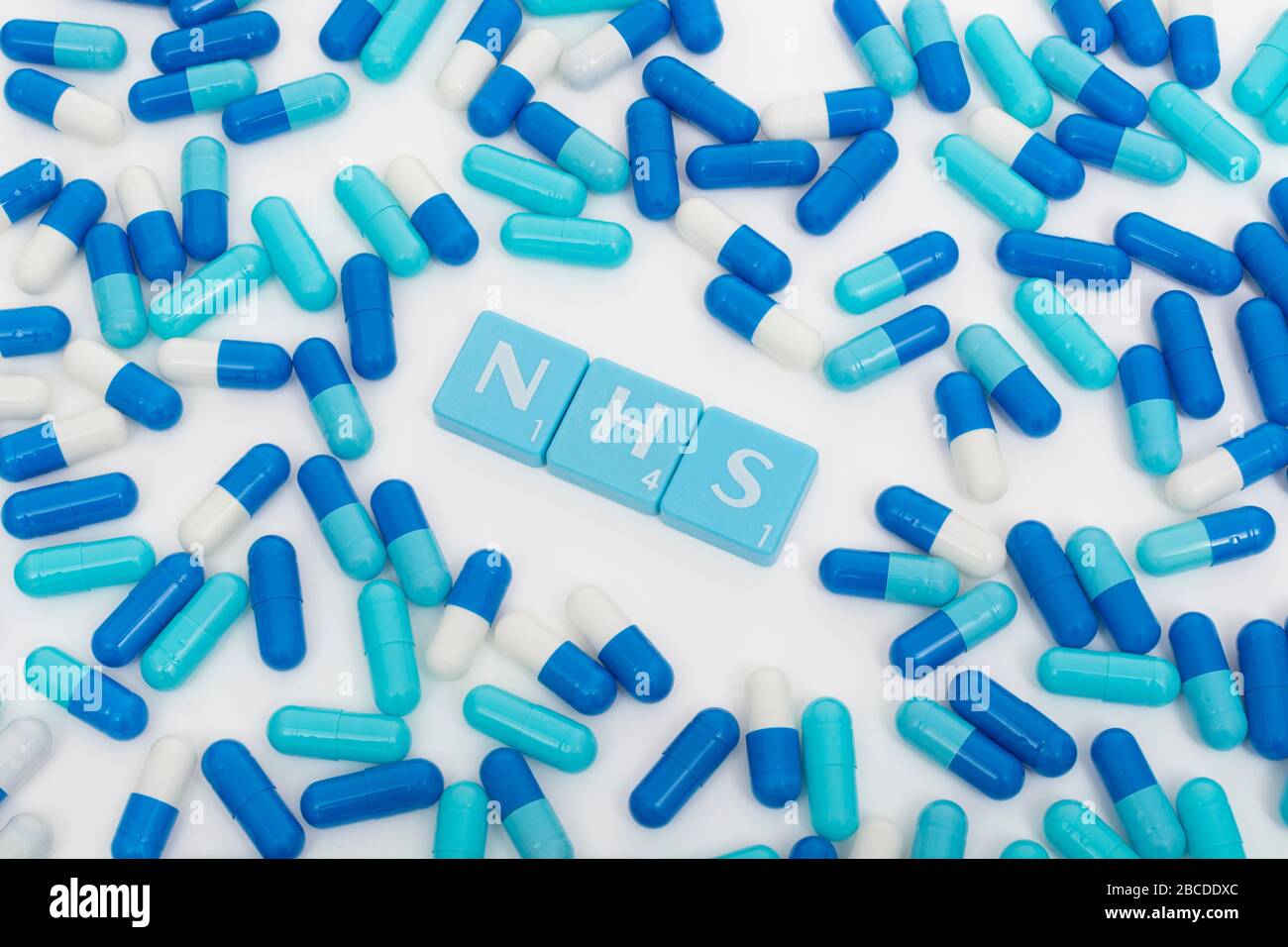 NHS letters tiles & assorted blue pills. Metaphor NHS in Covid 19 pandemic, NHS heroes, NHS prescriptions, UK National Health Service, medicine in UK Stock Photo