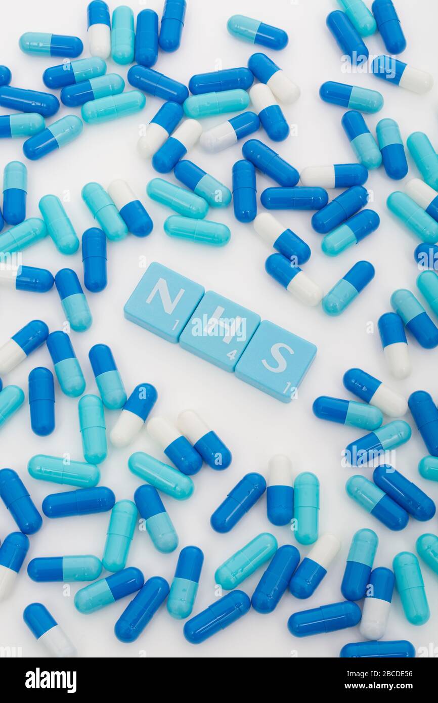 NHS letters tiles & assorted blue pills. Metaphor NHS in Covid 19 pandemic, NHS heroes, NHS prescriptions, UK National Health Service, medicine in UK Stock Photo