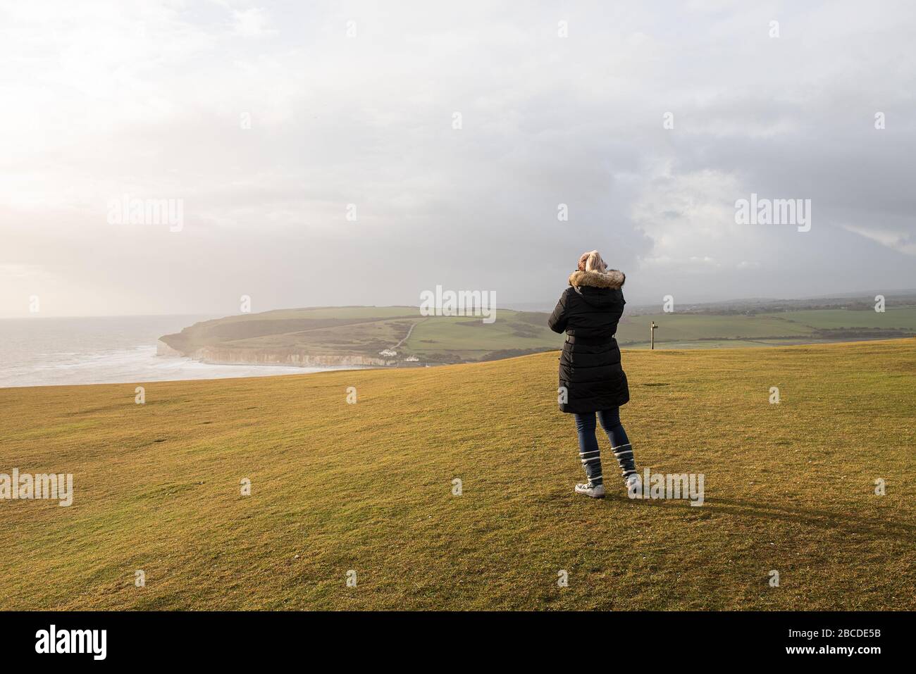 Woman in jacket standing on the cliffs of Seven Sisters in England. Stock Photo