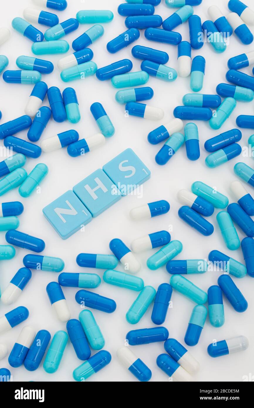 NHS letters tiles & assorted blue pills. Metaphor NHS in Covid 19 pandemic, NHS heroes, NHS prescriptions, UK National Health Service, medicine in UK Stock Photo