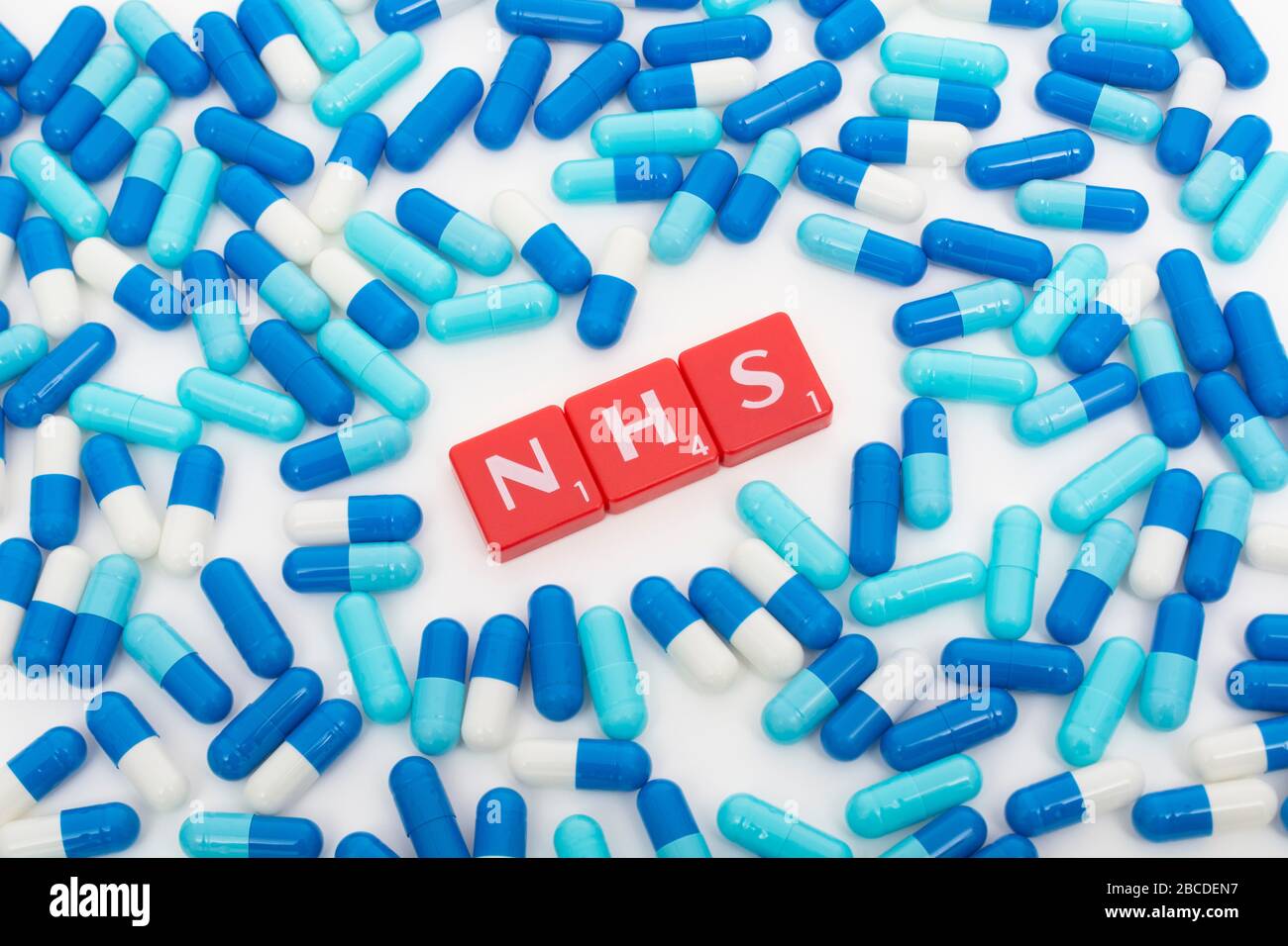 NHS letters tiles & assorted blue pills. Metaphor NHS in Covid 19 pandemic, NHS heroes, NHS prescriptions, UK National Health Service, medicine in UK Stock Photo