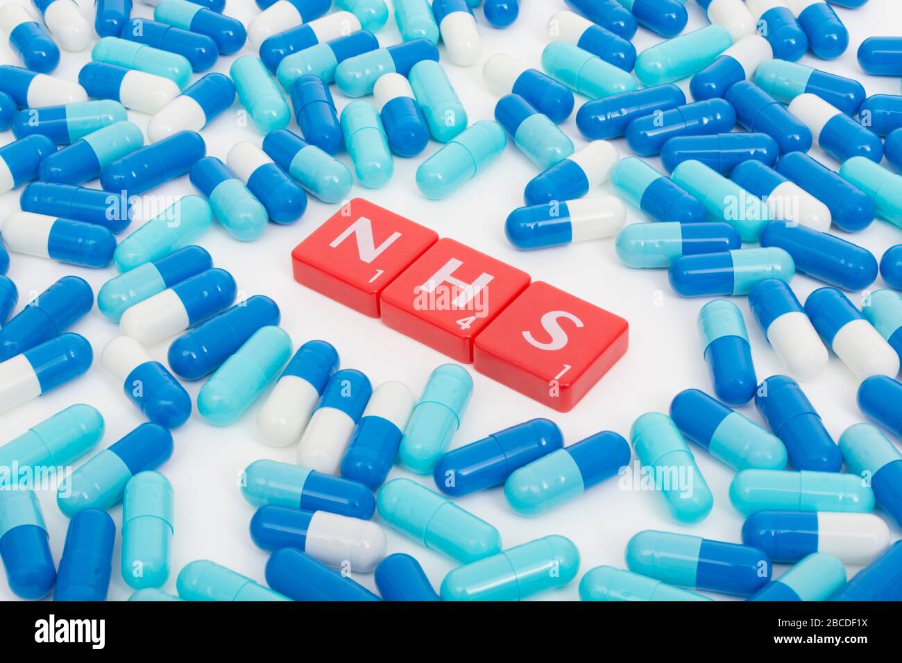 NHS letters tiles & assorted blue pills. Metaphor NHS in Covid 19 pandemic, NHS heroes, NHS prescriptions, UK National Health Service, medicine in UK Stock Photo