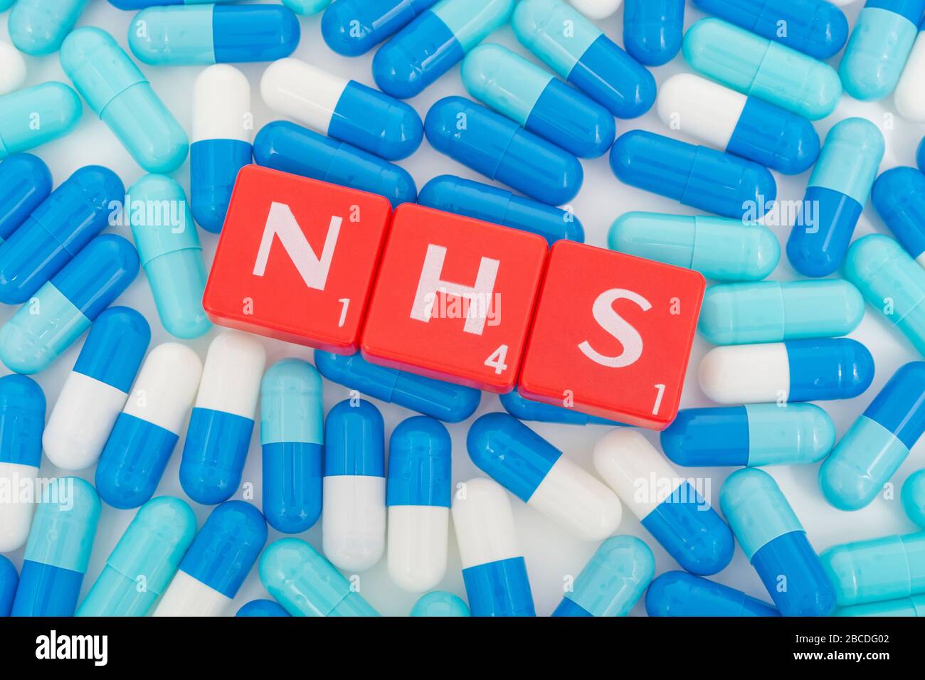 NHS letters tiles & assorted blue pills. Metaphor NHS in Covid 19 pandemic, NHS heroes, NHS prescriptions, UK National Health Service, medicine in UK Stock Photo