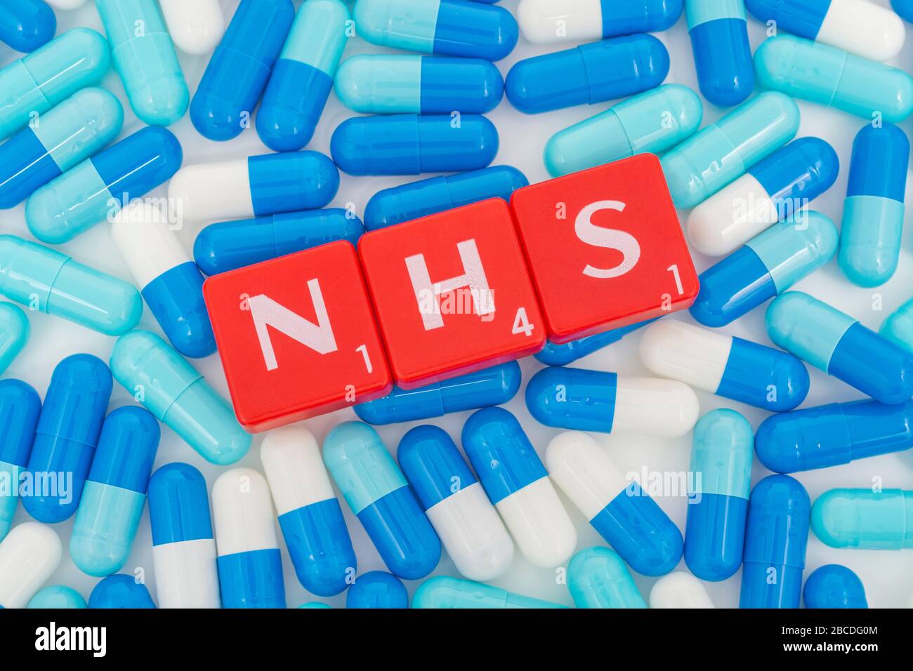 NHS letters tiles & assorted blue pills. Metaphor NHS in Covid 19 pandemic, NHS heroes, NHS prescriptions, UK National Health Service, medicine in UK Stock Photo