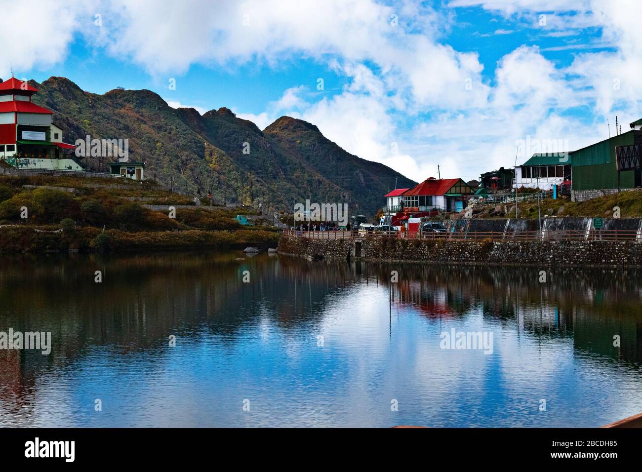 A landscape view of Tsomgo Lake, also called Changu Lake surrounded by stony hills and roads in Autumn season under blue sky. A sacred location for lo Stock Photo