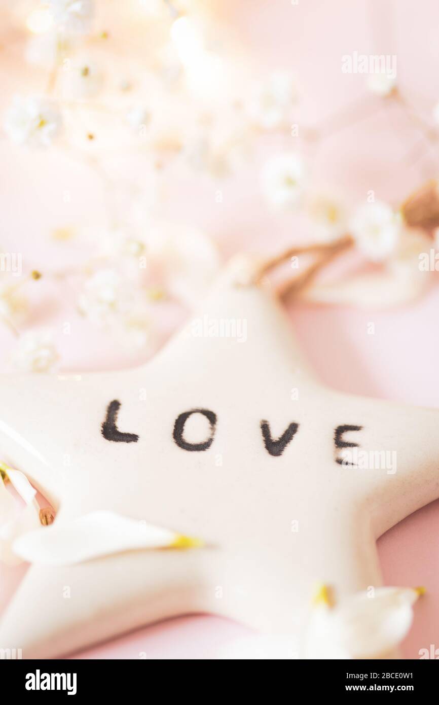 Life Quote - Love on a white ceramic star - still life concept image against a soft delicate pink background Stock Photo